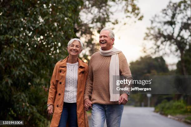 shot of a mature couple taking a sunset stroll - mature couple winter outdoors stock pictures, royalty-free photos & images