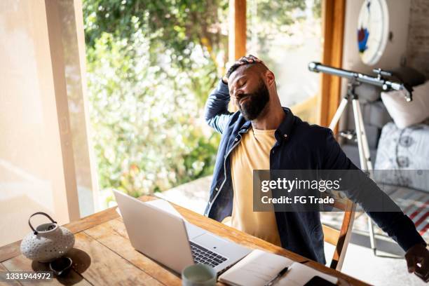 mature man stretching while working at home - study older man imagens e fotografias de stock