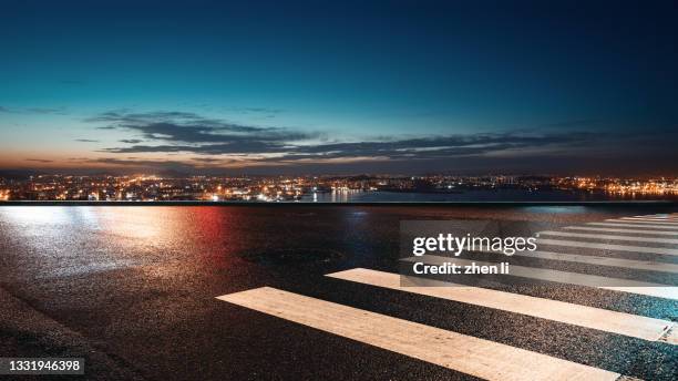 asphalt road with the urban skyline as the background at night - strada urbana foto e immagini stock