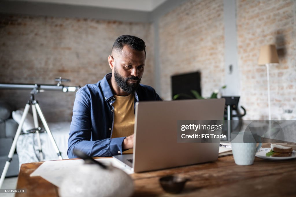 Hombre maduro usando computadora portátil trabajando en casa