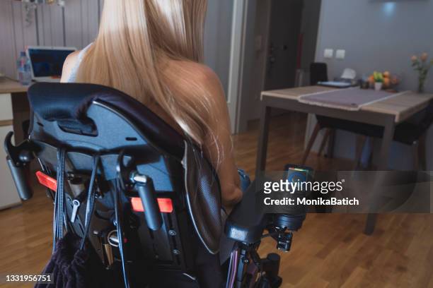 beautiful young disabled woman in wheelchair  in her appartment - spinal cord injury stock pictures, royalty-free photos & images