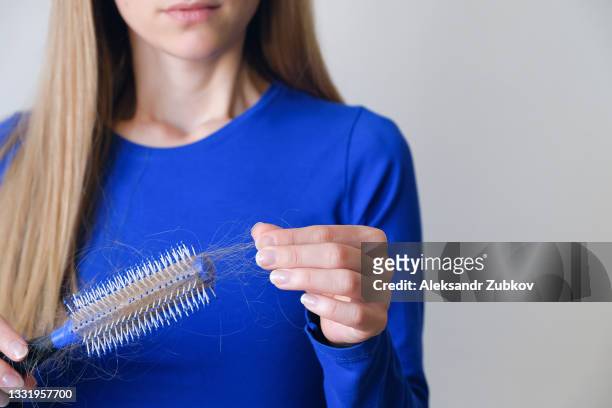 a woman holds a comb in her hands, cleans it from fallen hair after combing, in the bathroom. the concept of head health problems, insufficient conditions in the body due to stress and depression, the consequences of chemotherapy and radiation for cancer. - hairbrush 個照片及圖片檔