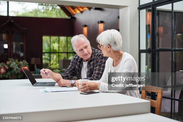 shot of a senior couple using a laptop at home - erfenis stockfoto's en -beelden