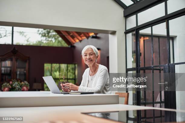 shot of a senior woman using a laptop at home - 401k stock pictures, royalty-free photos & images