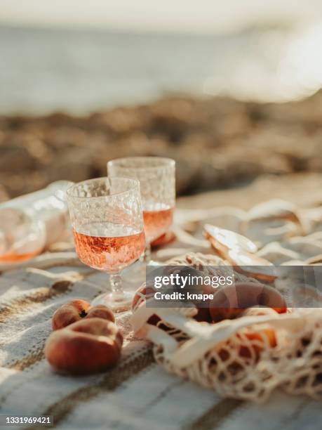 vino y melocotones junto al mar picnic al aire libre al atardecer - vino rosado fotografías e imágenes de stock