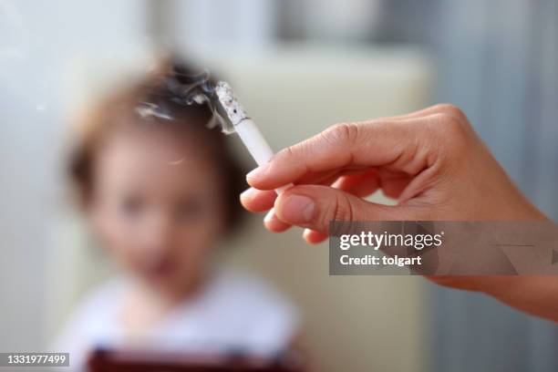 petite fille derrière une main avec un cigarett allumé - fumer du tabac photos et images de collection