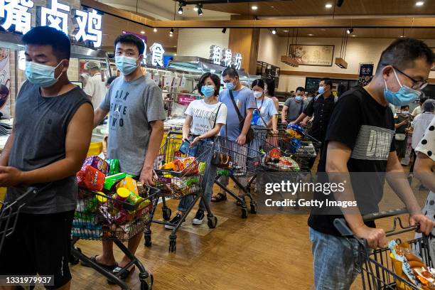 People wear protective masks as they line up to pay in a supermarket on August 2, 2021 in Wuhan, Hubei Province, China. According to media reports,...