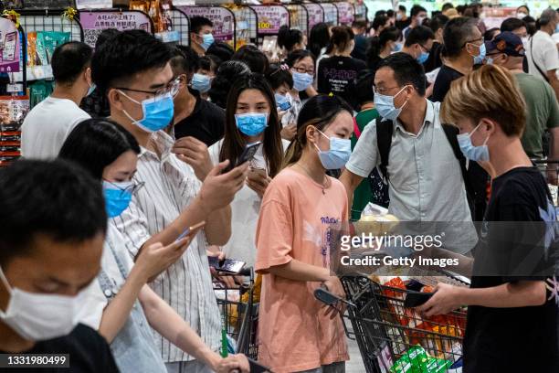 People wear protective masks as they line up to pay in a supermarket on August 2, 2021 in Wuhan, Hubei Province, China. According to media reports,...