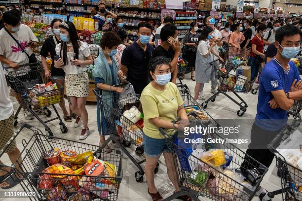 People wear protective masks as they line up to pay in a supermarket on August 2, 2021 in Wuhan, Hubei Province, China. According to media reports,...