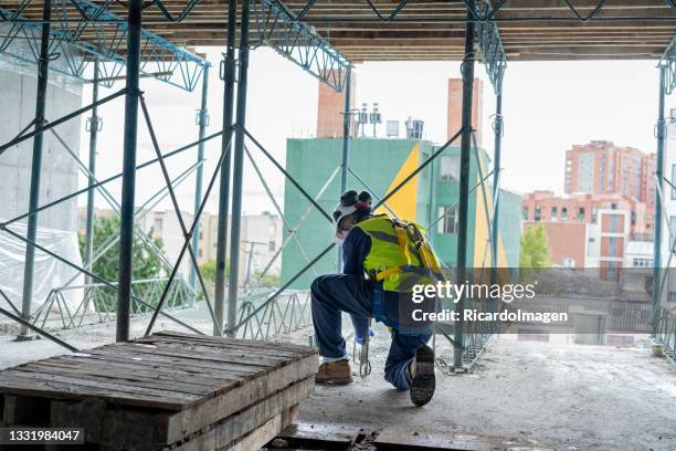 el hombre latino a cargo de la construcción está en medio de la obra trabajando - zapato metálico fotografías e imágenes de stock