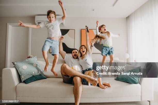 family celebrating a goal - celebrating in sofa stock pictures, royalty-free photos & images