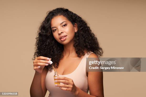 mixed race woman holding in hands face serum - apothecary bottle stock pictures, royalty-free photos & images