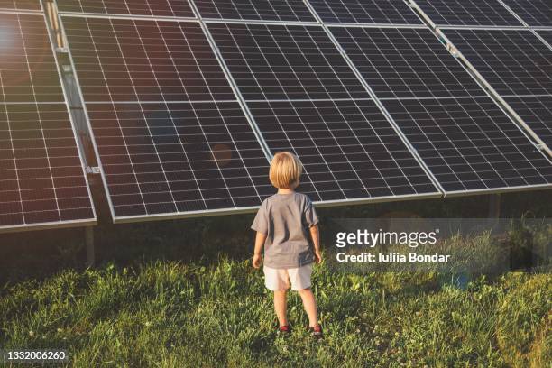 4 year old blonde boy standing in front of small solar panel farm - 太陽エネルギー ストックフォトと画像
