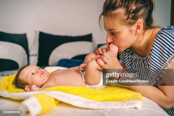 mother kissing her baby's feet - feet kiss stockfoto's en -beelden