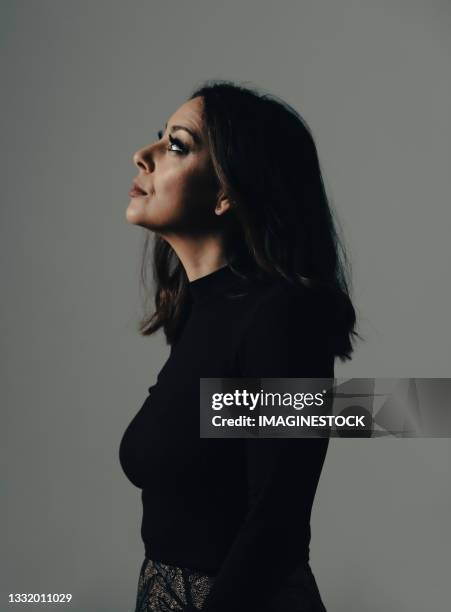 profile portrait of beautiful woman on her hand on a dark background - people on plain background stock pictures, royalty-free photos & images