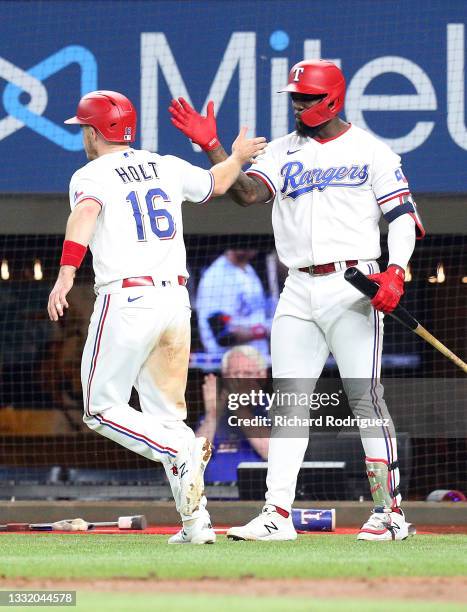Brock Holt of the Texas Rangers is greeted by Adolis Garcia after stealing home against the Los Angeles Angels in the sixth inning at Globe Life...
