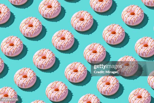 doughnut repetition pattern on turquoise - dónute imagens e fotografias de stock