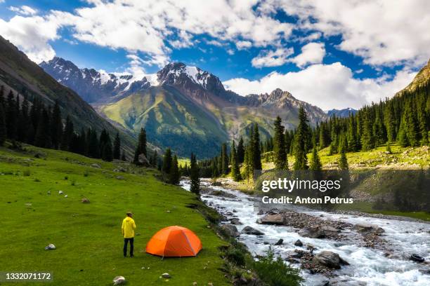 man near the tent in a beautiful mountain valley. hiking in the mountains - kyrgyzstan 個照片及圖片檔