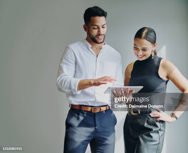 shot of a young businessman and businesswoman using a digital tablet against a grey background in a modern office - two people studio shot stock pictures, royalty-free photos & images