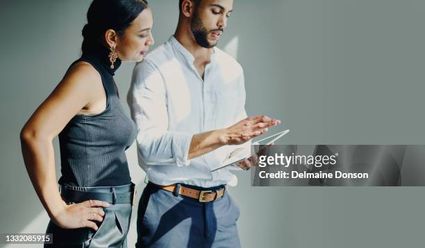 shot of a young businessman and businesswoman using a digital tablet against a grey background in a modern office - two people studio shot stock pictures, royalty-free photos & images
