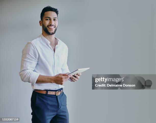 tiro de um jovem empresário usando um tablet digital contra um fundo cinza em um escritório moderno - roupa formal - fotografias e filmes do acervo