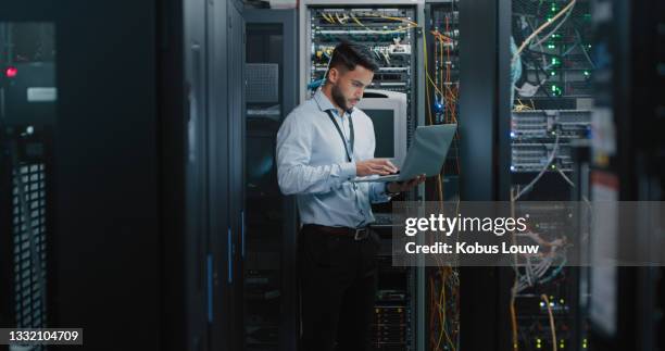 shot of a young male engineer using his laptop in a server room - network server man stock pictures, royalty-free photos & images