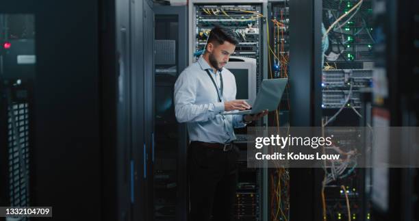 shot of a young male engineer using his laptop in a server room - network server stock pictures, royalty-free photos & images