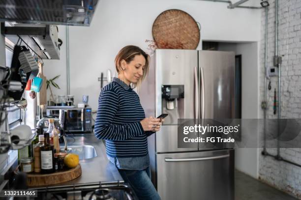 mature woman texting on the phone at home - generation x stock pictures, royalty-free photos & images