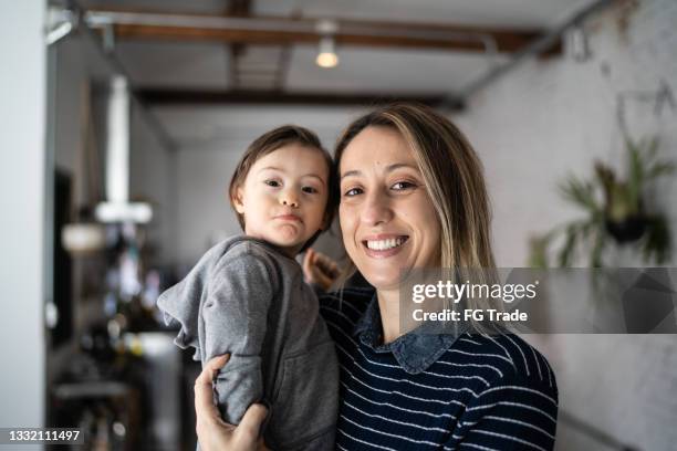 portrait of mother taking care of baby son at home - boy with special needs - mom looking at camera stock pictures, royalty-free photos & images