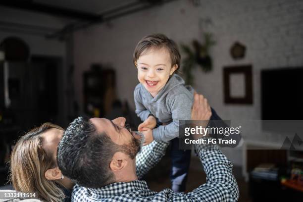 mature couple playing with son with special needs at home - down syndrome baby stockfoto's en -beelden