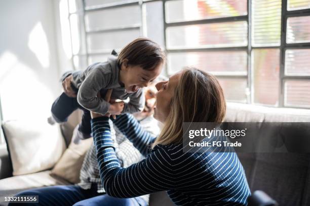 mature couple playing with son with special needs at home - down syndrome baby stock pictures, royalty-free photos & images