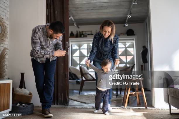 father filming baby son's first steps - boy with special needs - down syndrome baby stockfoto's en -beelden