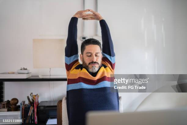 mature man stretching while working at home - man arms outstretched stock pictures, royalty-free photos & images