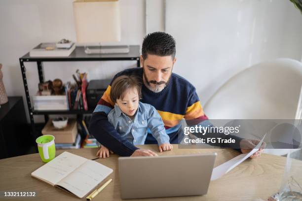 mature man working at home with baby son - boy with special needs - financial planner stockfoto's en -beelden