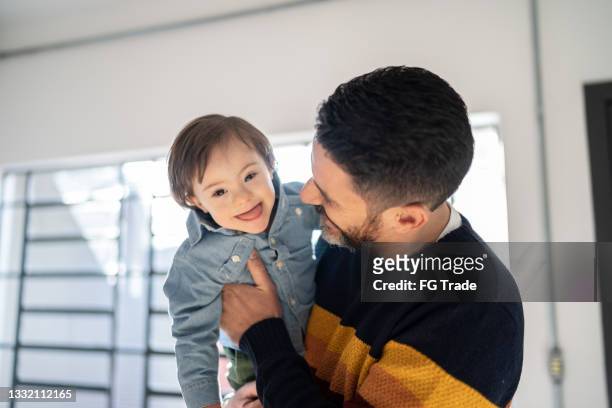 portrait of father carrying cute baby boy with special needs - down syndrome baby stock pictures, royalty-free photos & images