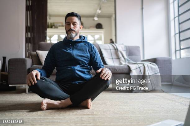 hombre maduro meditando en casa - ejercicios de respiración fotografías e imágenes de stock