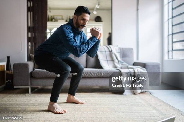 mature man squatting at home - home workout stockfoto's en -beelden