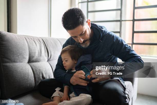 father changing son's clothes at home - boy with special needs - modern manhood stock pictures, royalty-free photos & images