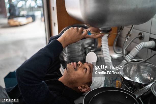 pumber fixing water pipe under the sink - kitchen straighten stockfoto's en -beelden