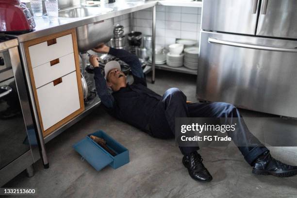 pumber fixing water pipe under the sink - kitchen straighten stockfoto's en -beelden