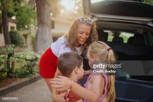 mutter entlädt das auto mit ihren kindern nach dem einkaufen. - unloading stock-fotos und bilder