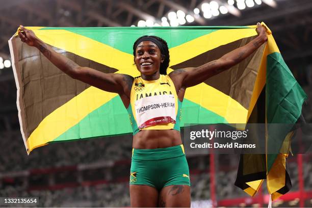 Elaine Thompson-Herah of Team Jamaica celebrates with her countries flag after winning the gold medal in the Women's 200m Final on day eleven of the...