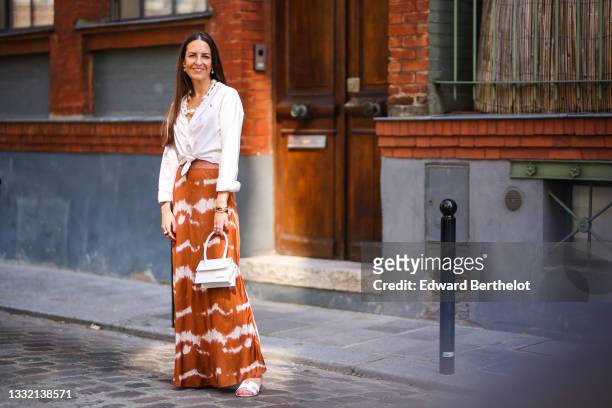 Alba Garavito Torre wears a necklace with white large pearls, a white shirt closed with a knot from Ralph Lauren, a brown and white striped tie and...