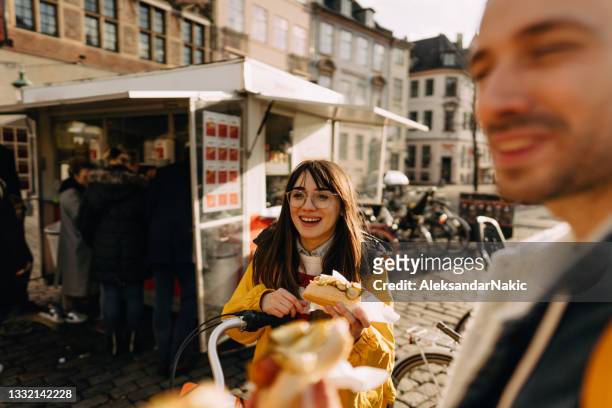 smiling friends trying out local street food - copenhagen food stock pictures, royalty-free photos & images
