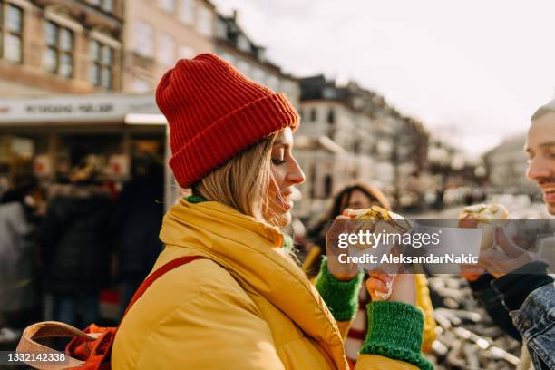 smiling friends trying out local street food - copenhagen winter stock pictures, royalty-free photos & images
