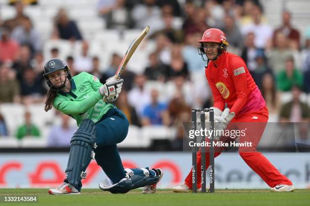 Sarah Bryce of Oval Invincibles Women hits out as Sarah Taylor of Welsh Fire Women looks on during The Hundred match between Oval Invincibles Women...