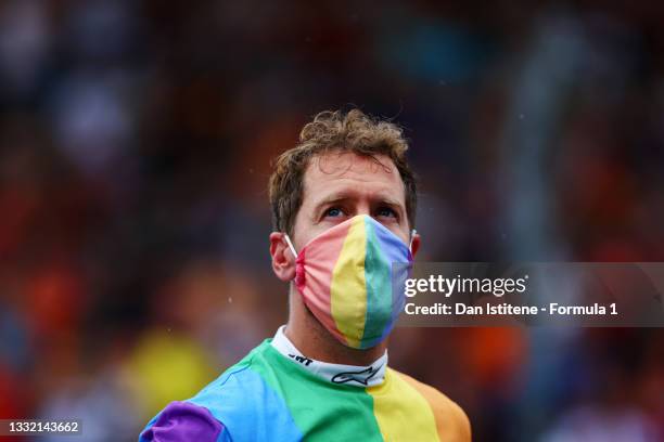 Sebastian Vettel of Germany and Aston Martin wears a rainbow coloured t-shirt and face mask as he looks on from the grid before the F1 Grand Prix of...