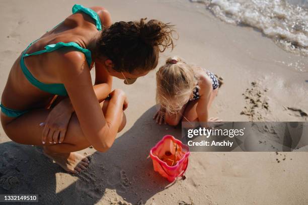 mother and daughter observing a jellyfish caught in sand bucket - jellyfish stock pictures, royalty-free photos & images
