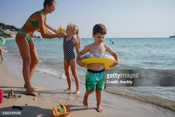 madre, hija e hijo divirtiéndose en la playa - brazaletes acuáticos fotografías e imágenes de stock