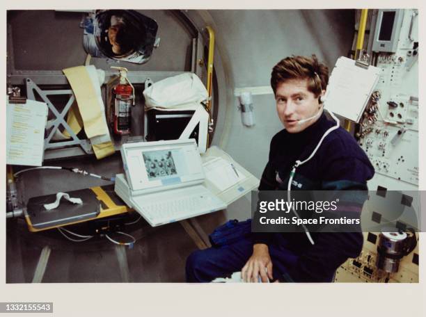 American NASA astronaut Terence T Henricks sits at the adjustable workstation mounted on the Spacelab Deutsche 2 science module, conducting a Crew...
